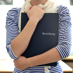 Person hält Bewerbungsmappe